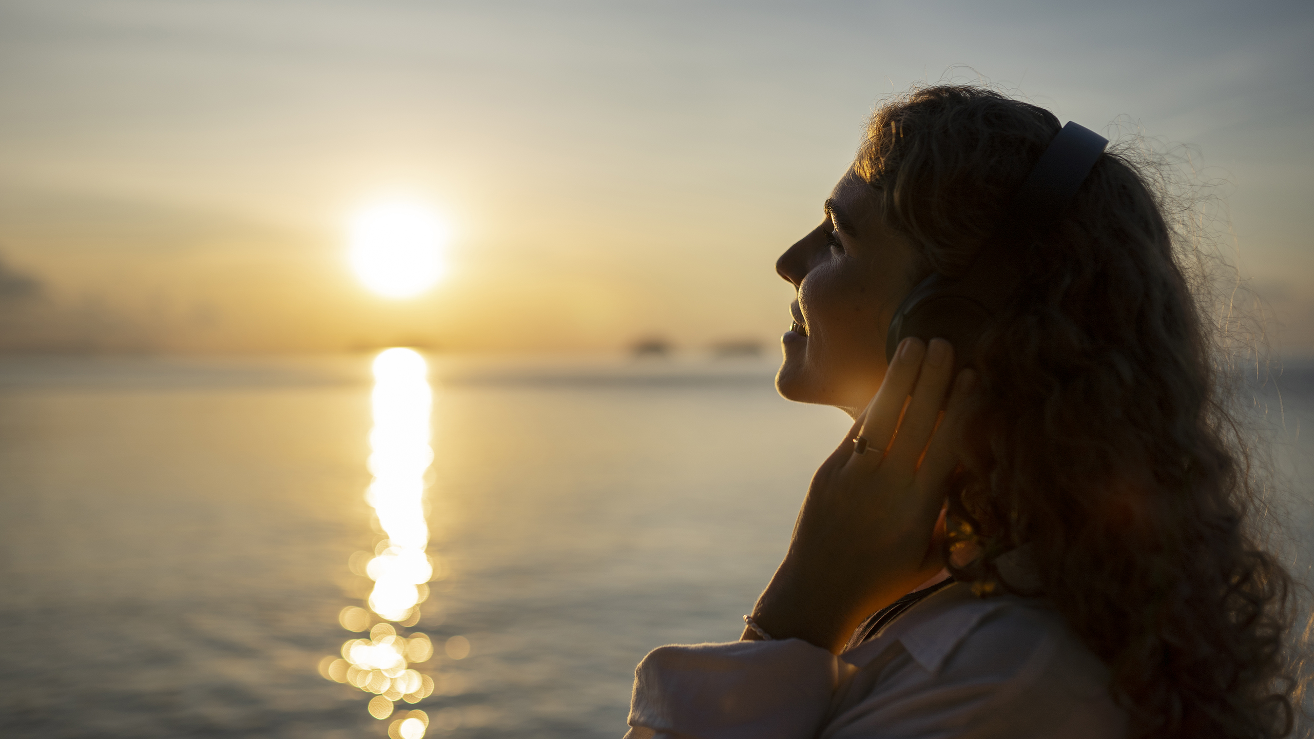 Woman walking alone on a quiet beach at sunrise, symbolizing calm, clarity, and the body settling down.